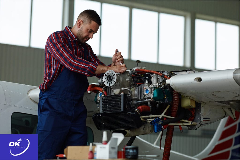 Aircraft technician performing engine maintenance on a small airplane inside a hangar, inspecting and working on rotable parts such as the alternator, magnetos, and fuel system components. The image highlights precision repair in aviation, with the DK Turbines logo in the corner.
