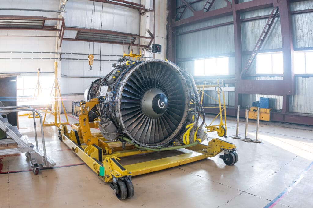 Commercial jet engine on a yellow transport stand inside a maintenance hangar, emphasizing the critical role of selecting the right turbine engine for performance, reliability, and compliance.