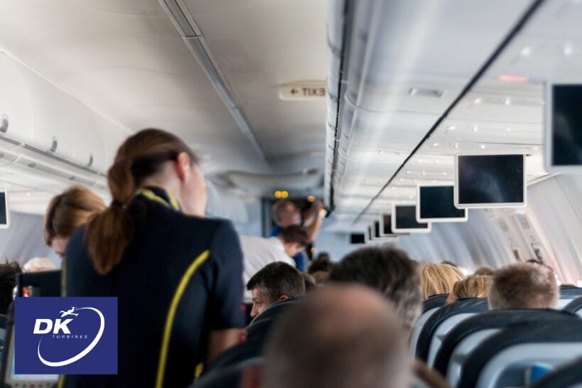 Airplane cabin with passengers seated and crew standing during flight