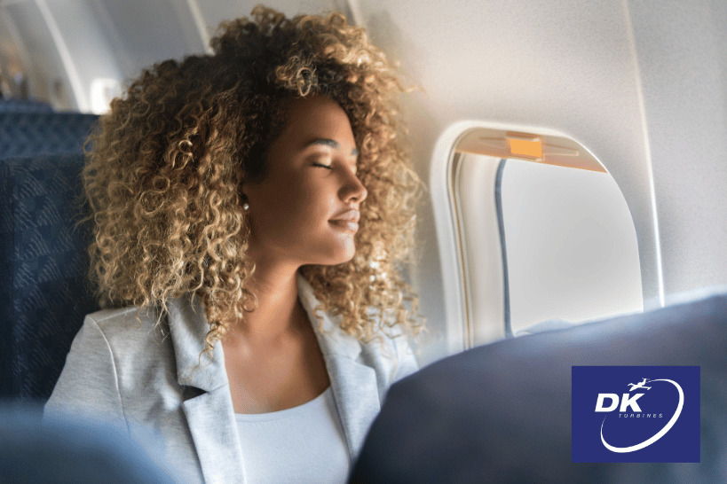 Woman sitting peacefully by airplane window with eyes closed, staying comfortable at cruising altitude