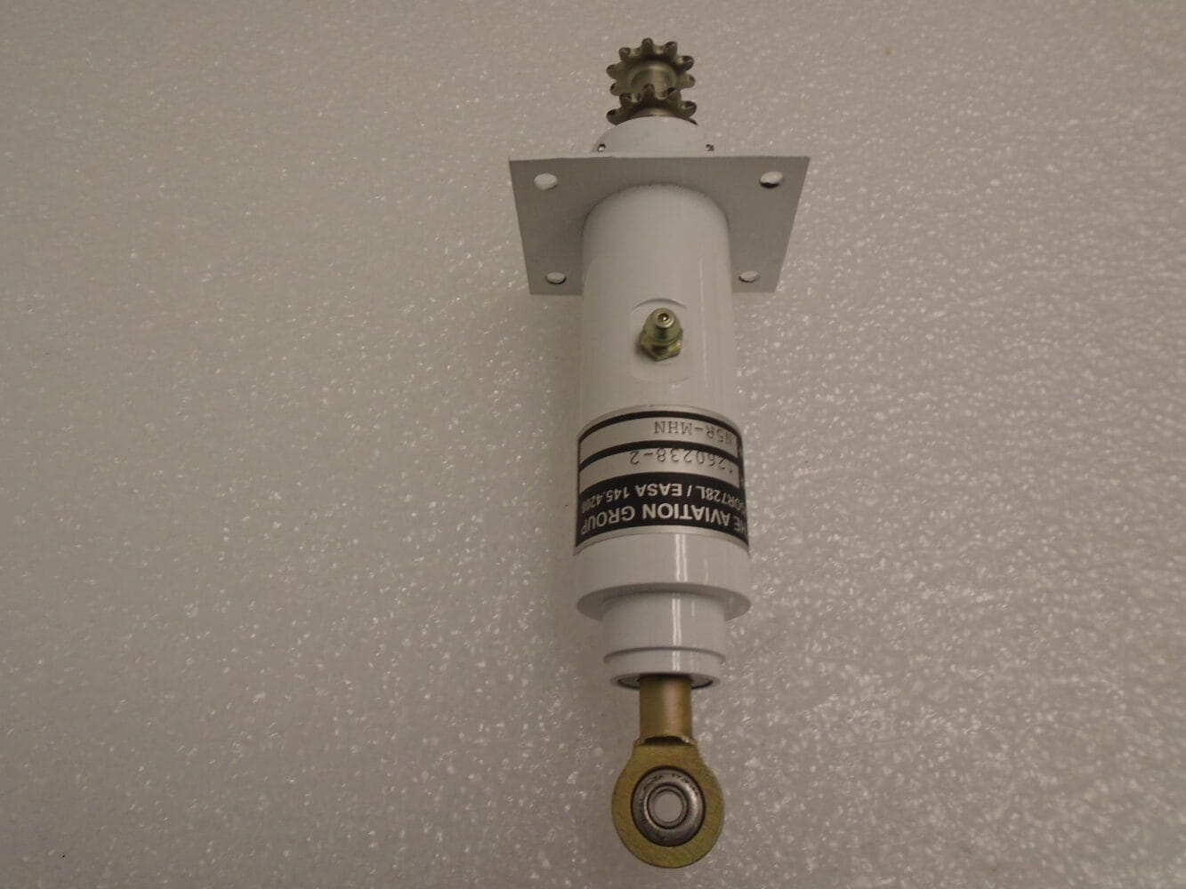 Aircraft trim actuator featuring gear mechanism and rod-end bearing, shown against a white background.